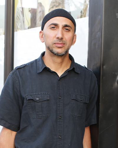 Portrait of Rami Nashashibi in front of building.