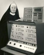 Sister Mary Kenneth Keller standing besides an early computer