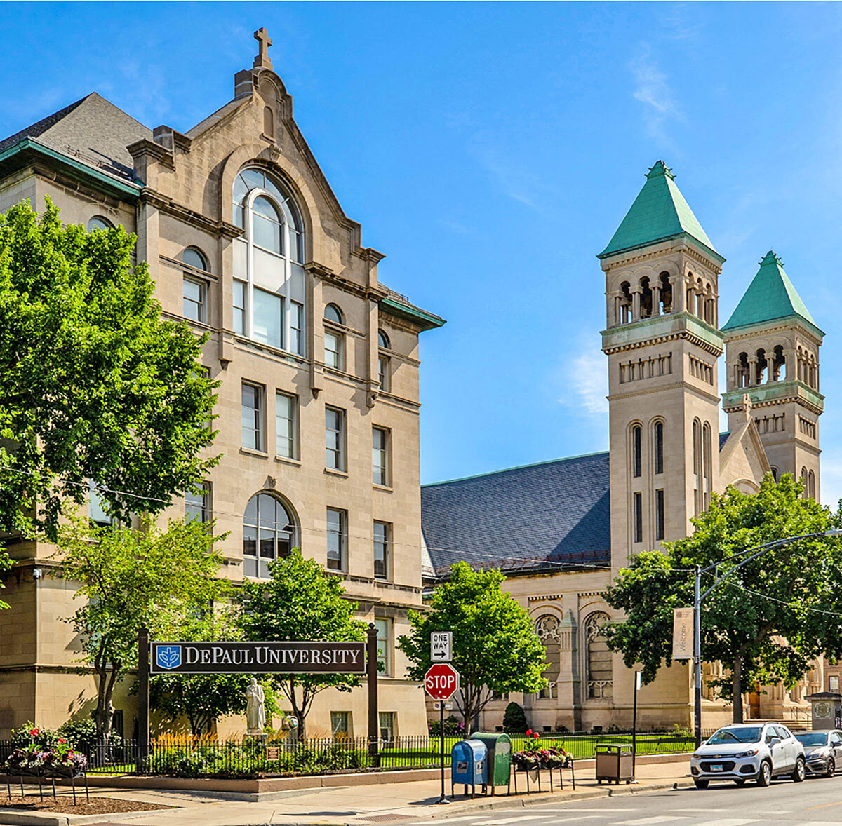 The St. Vincent de Paul Church on the Lincoln Park Campus is shown in 2022. There is a sign in front of the building that reads ‘DePaul University’ with a blue shield symbol decorated with a white outline of the Tree of Wisdom next to it.